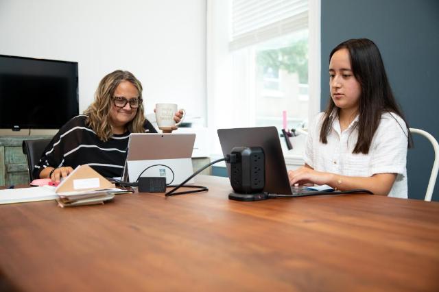 Student on an internship, sitting next to her supervisor, using a laptop.