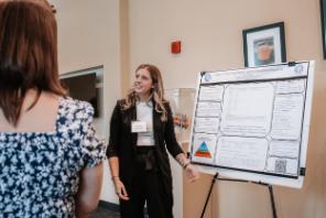 - A Longwood graduate student presents mental health research to an attendee at a poster session.