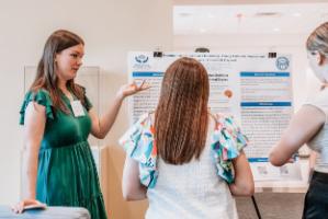 - A Longwood graduate student presents research to attendees at a poster session.