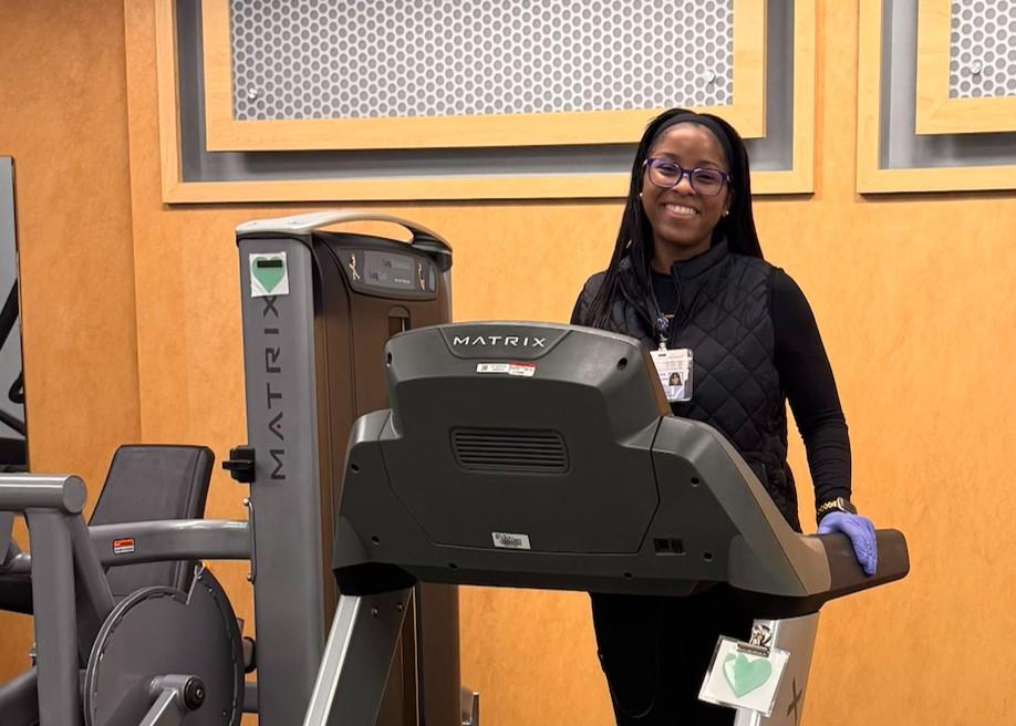 Jiovanni is smiling on a treadmill wearing a badge and medical gloves